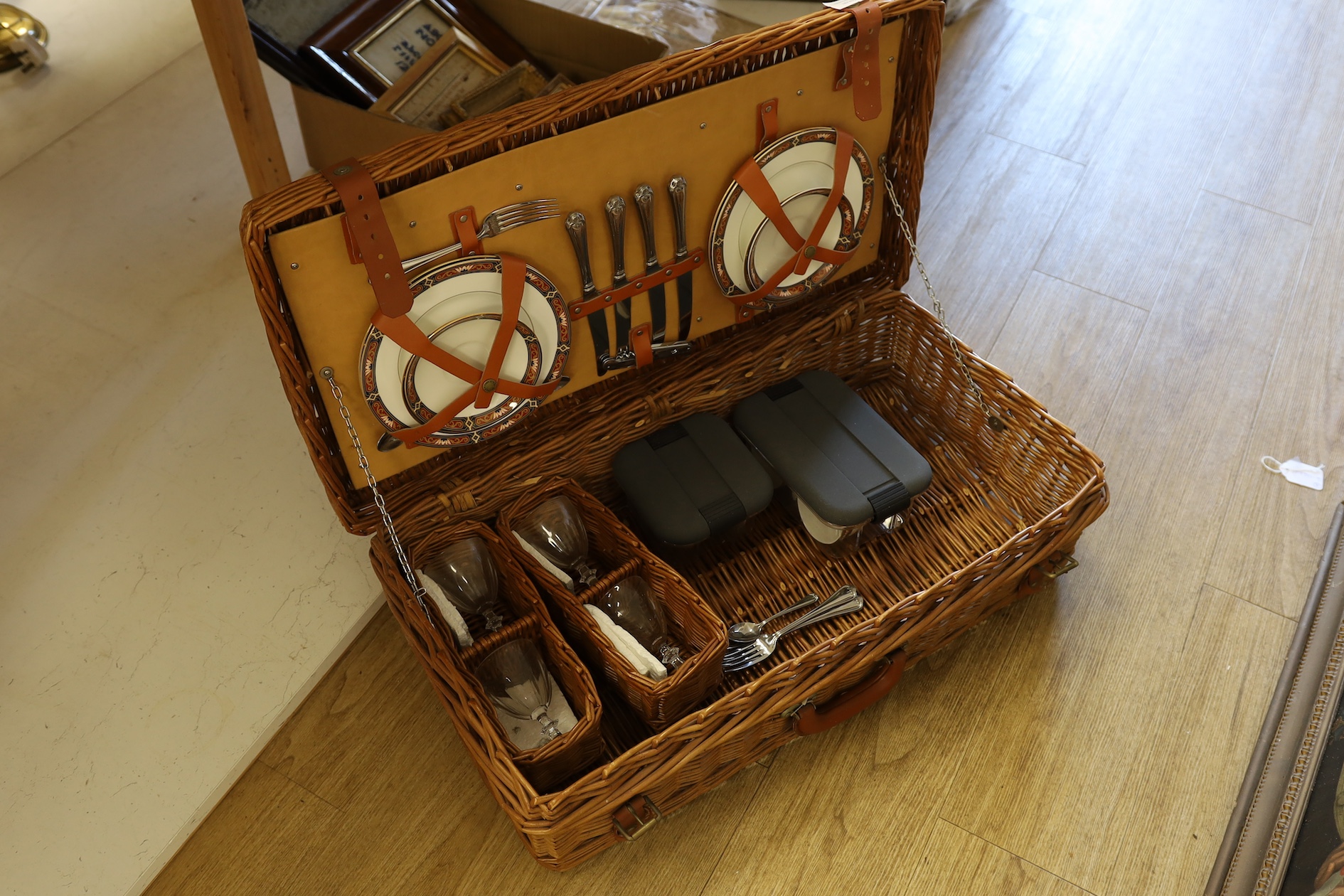 A Harrods wicker picnic hamper for four persons, with Wedgwood plates, cups and saucers, plated cutlery and wine glasses. Condition - good